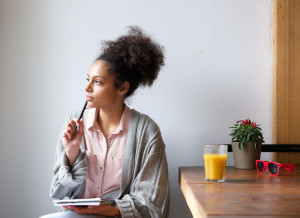 33727926 - portrait of a young woman sitting at home with pen and paper